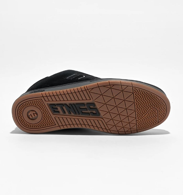 Black sneaker with a brown sole with 'Etnies' branding on a white background