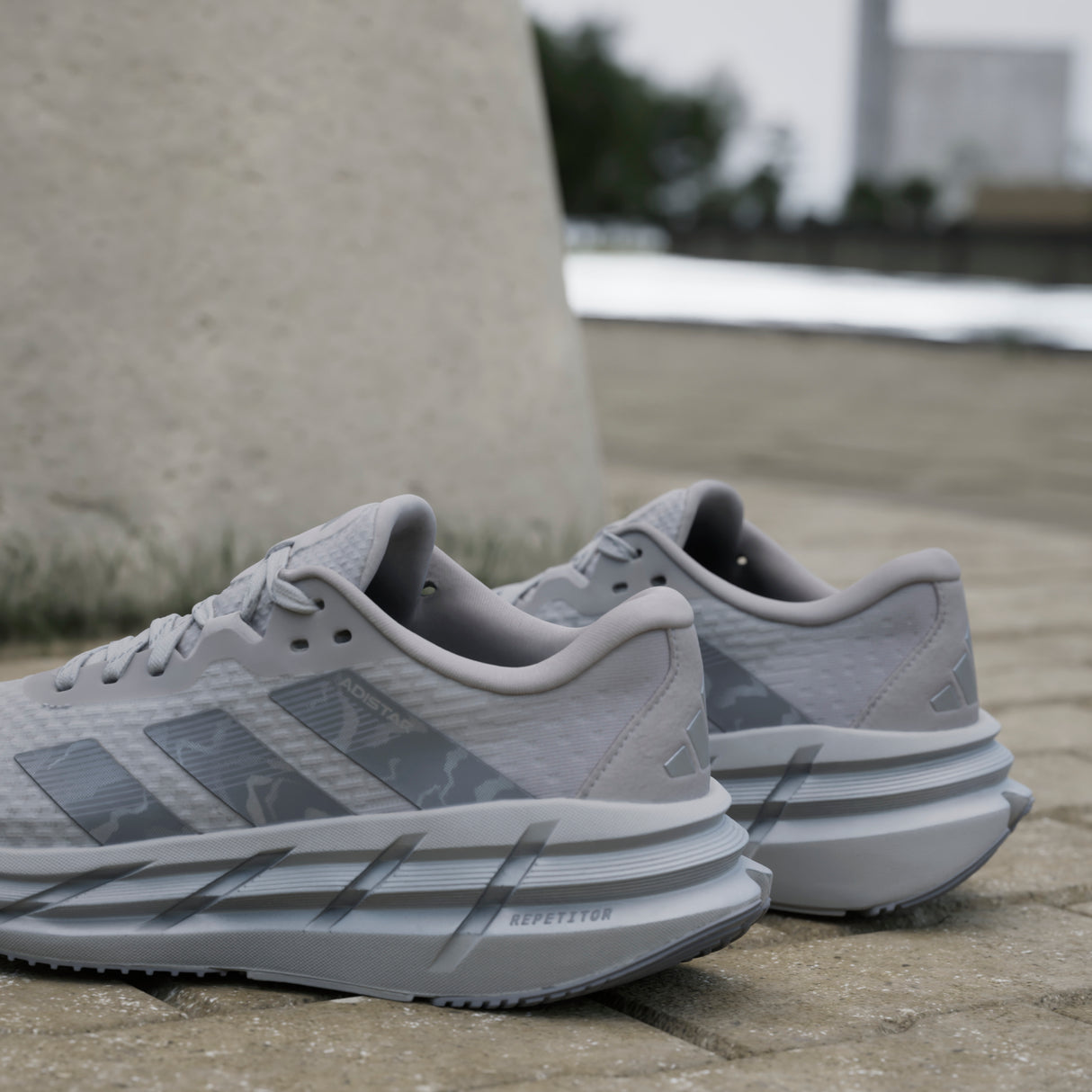Gray running shoes with Adidas logo on a concrete surface
