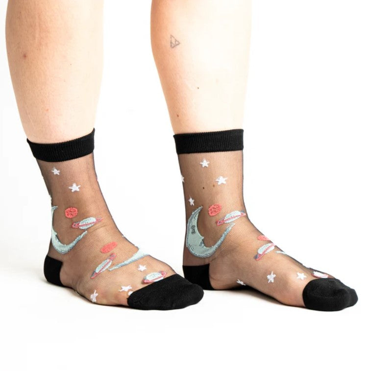 Sheer socks with moon and star designs worn by a person on a white background