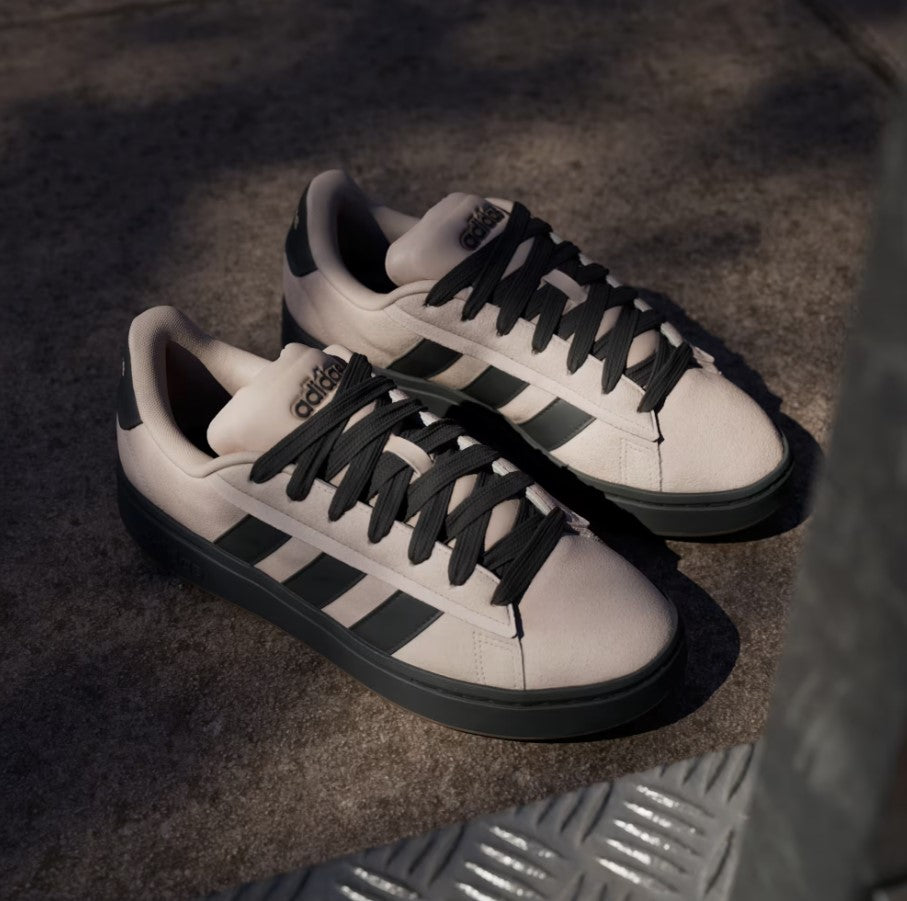 Taupe sneakers with black stripes on a textured surface