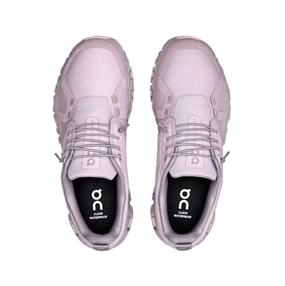 Pair of pink sneakers with 'on' branding on a light gray background