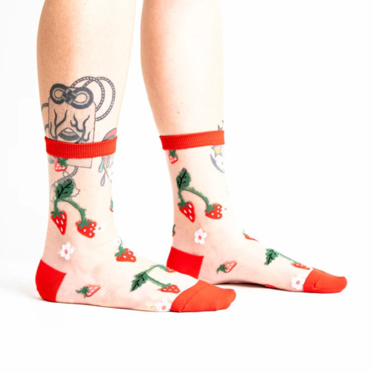 Socks with strawberry pattern and red accents worn by a person on a white background