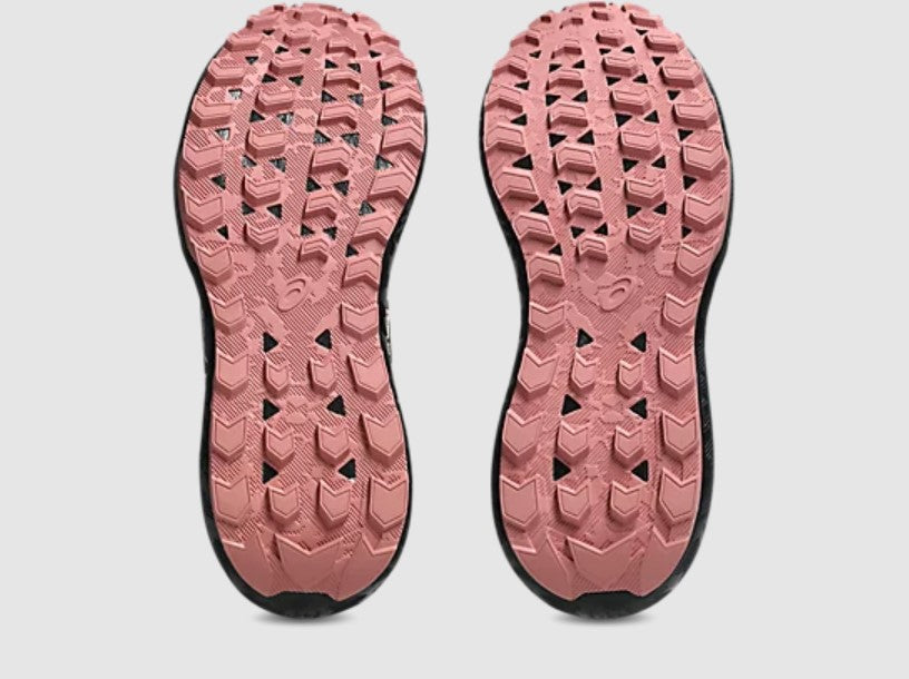 Close-up of pink shoe soles with tread pattern on a light gray background