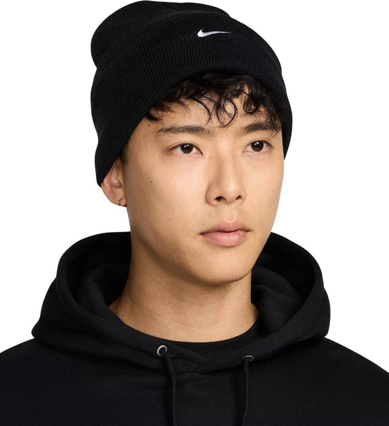 Person wearing a black Nike beanie on a white background