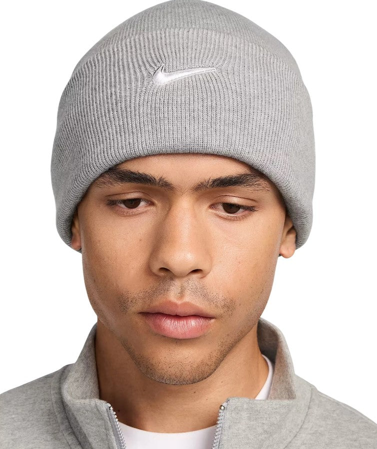 Person wearing a gray knit beanie with a Nike logo on a white background
