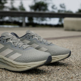 Gray running shoes with Adidas logo on a blurred outdoor background