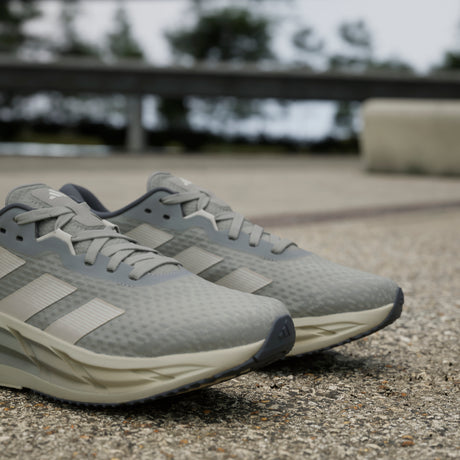 Gray running shoes with Adidas logo on a blurred outdoor background