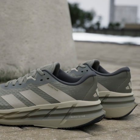 Pair of Adidas running shoes on a concrete surface with a blurred background