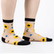Sheer socks with sunflower and bee pattern worn by a person on a white background
