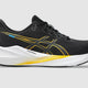 Black running shoe with yellow accents on a gray background