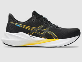 Black running shoe with yellow accents on a gray background