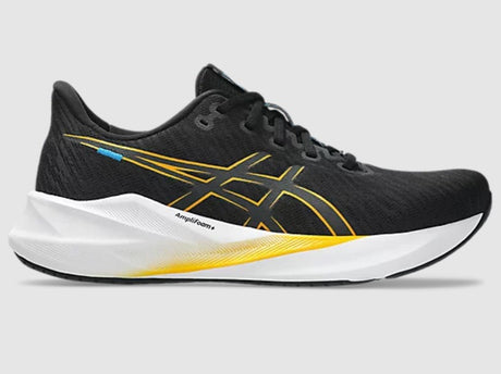 Black running shoe with yellow accents on a gray background