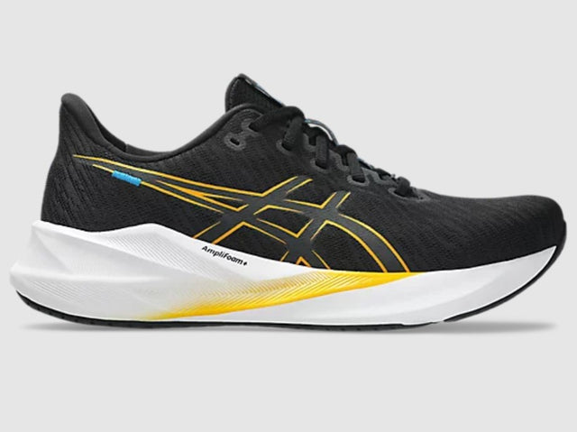 Black running shoe with yellow accents on a gray background