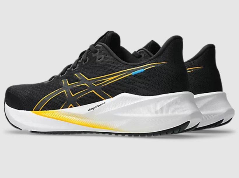 Black running shoes with yellow and white sole on a light gray background