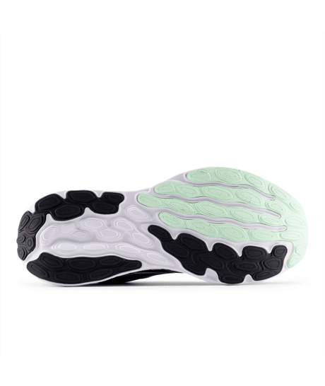 Close-up of a running shoe sole with black, white, and green design on a white background