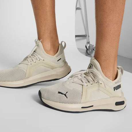 Beige Puma sneakers worn by a person on a light gray background