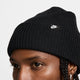 Black knit beanie with Nike logo tag worn by a person on a light gray background