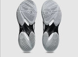 Close-up of black and gray athletic shoes with tread pattern on a light gray background