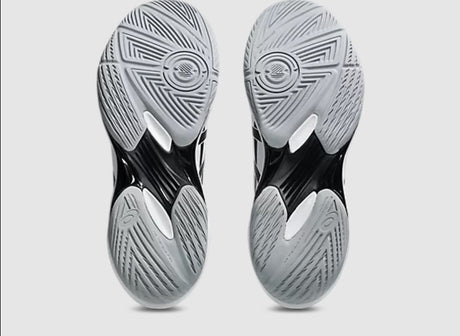 Close-up of black and gray athletic shoes with tread pattern on a light gray background