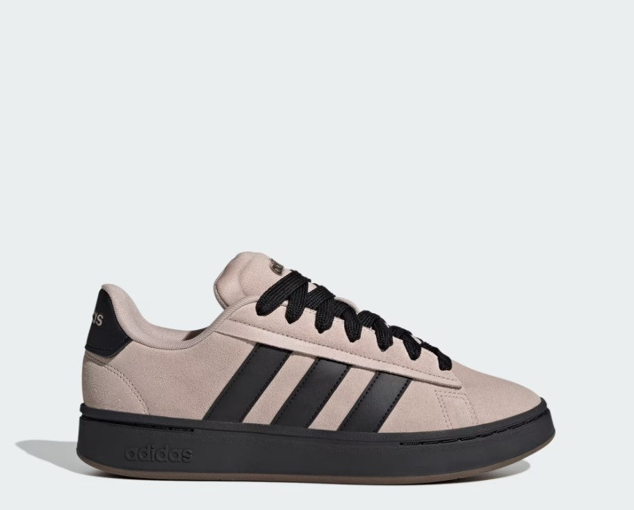 Beige Adidas sneaker with black stripes and sole on a light gray background