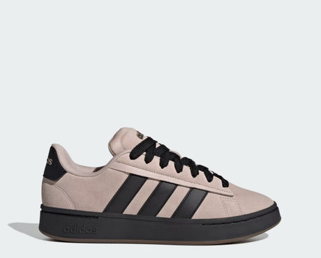Beige Adidas sneaker with black stripes and sole on a light gray background