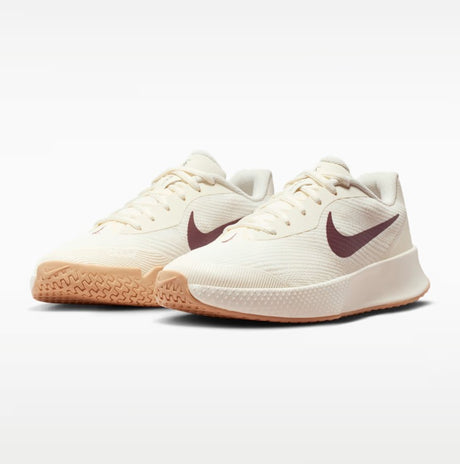 A pair of beige nikes shoe with a brown swoosh and a white and gum soles