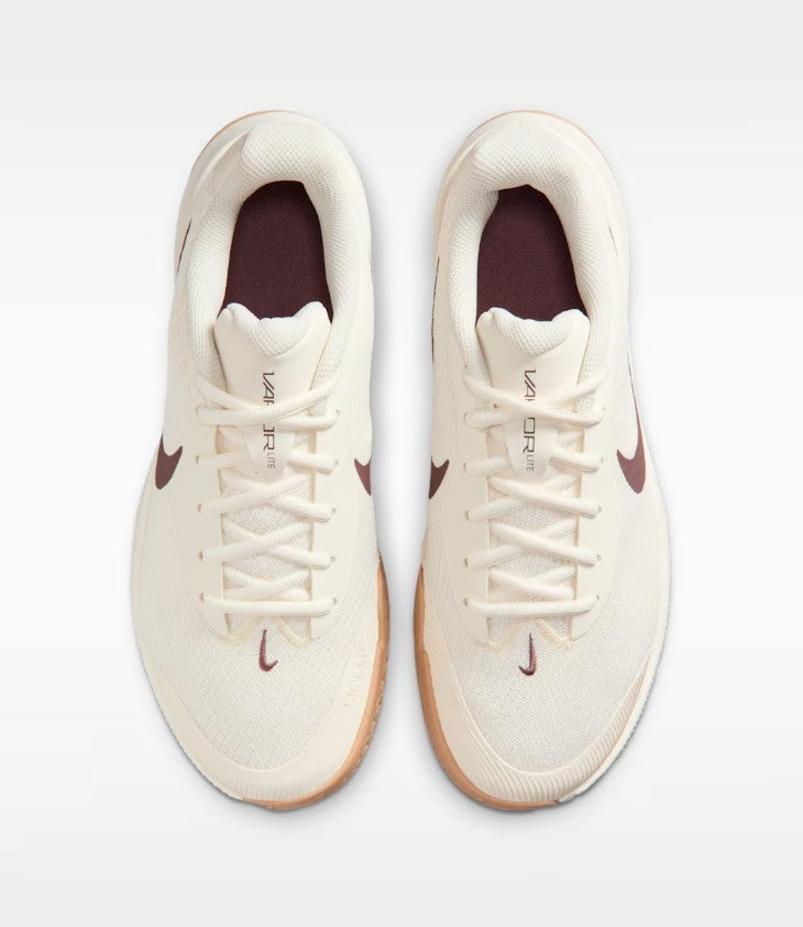 a pair of beige nike shoes with a brown swoosh and a white and gum sole from a top down view