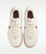 a pair of beige nike shoes with a brown swoosh and a white and gum sole from a top down view