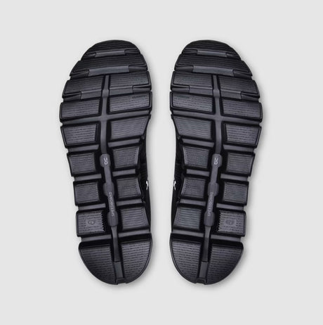 Top view of black sandals with textured sole on a light gray background