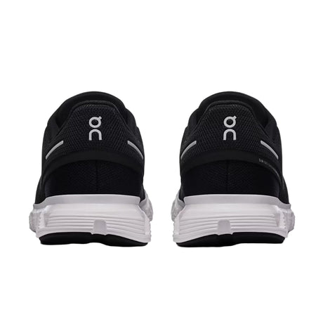 Black running shoes with white sole on a light gray background
