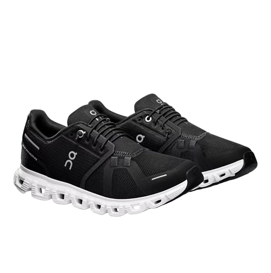 Black running shoes with white sole on a light gray background