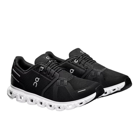 Black running shoes with white sole on a light gray background