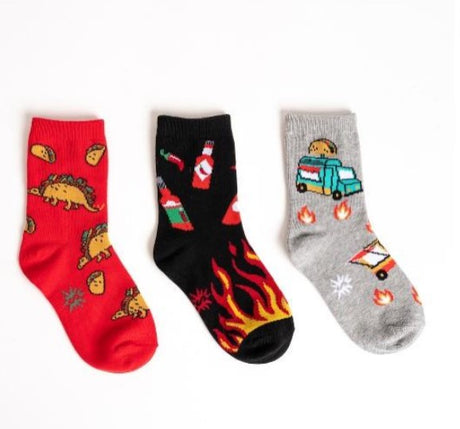 Three pairs of colorful socks with various taco dinosaurs and foo truck designs on a white background