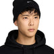 Person wearing a black Nike beanie on a white background