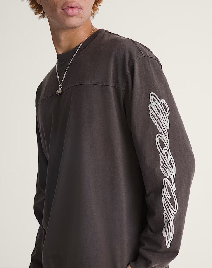 Person wearing a blackish - brown long-sleeve shirt with white script on the sleeve "Off The Wall" against a plain background